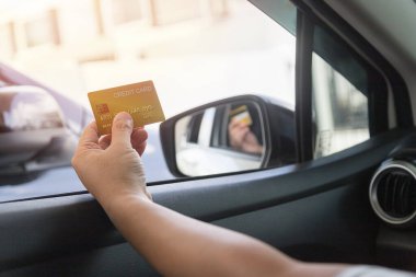 Driver pays by credit card separately on the car background.