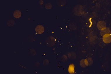 Siyah arkaplanda koyu soyut altın bokeh parıltısı