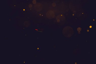 Siyah arkaplanda koyu soyut altın bokeh parıltısı