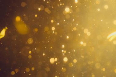 Siyah arkaplanda koyu soyut altın bokeh parıltısı