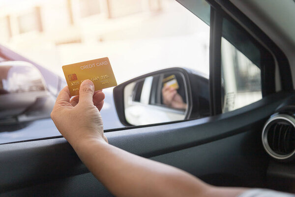 Водитель оплачивает кредитной картой отдельно на заднем плане автомобиля.