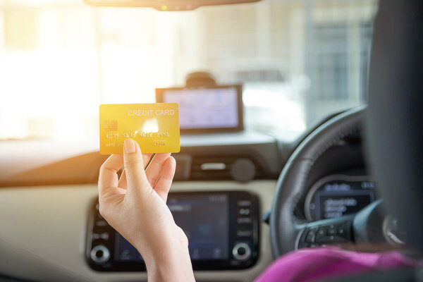 Водитель, оплачивающий проезд кредитной картой, изолирован на фоне автомобиля