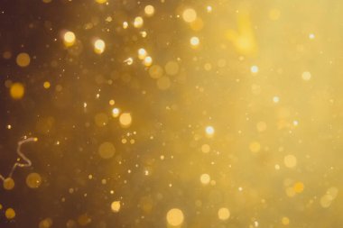 Siyah arkaplanda koyu soyut altın bokeh parıltısı