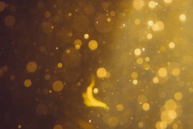 Siyah arkaplanda koyu soyut altın bokeh parıltısı