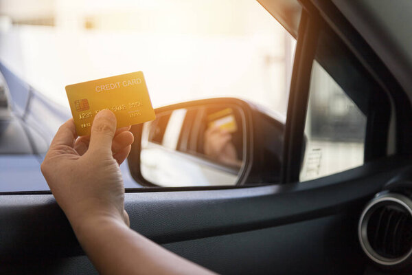 Водитель оплачивает кредитной картой отдельно на заднем плане автомобиля.