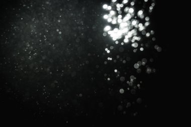 Siyah arkaplanlı kutlama için bulanık beyaz bokeh yıldızlarını kullan