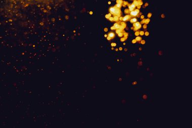 Siyah arkaplanla kutlama yapmak için kullanılan bulanık altın renkli parlak yıldızlar.