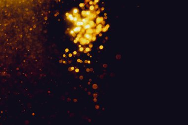 Siyah arkaplanla kutlama yapmak için kullanılan bulanık altın renkli parlak yıldızlar.