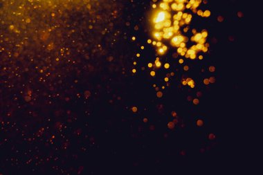 Siyah arkaplanla kutlama yapmak için kullanılan bulanık altın renkli parlak yıldızlar.