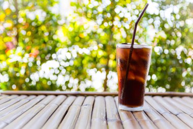 Bambu masası ve arka planında buz küpleri olan içecek bardağı.