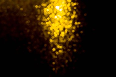 Siyah arkaplanda sudan gelen altın renkli ışıklar.