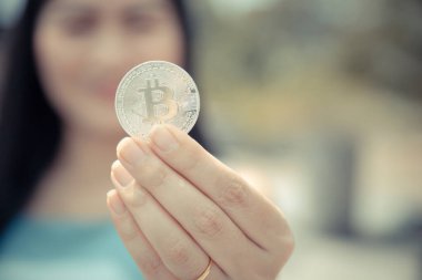 Elinde Bitcoin dijital para ve arka planı bulanık kripto para tutan güzel bir kadın. Kaşsız Toplum kavramı Web Sanal Para Madenciliği.