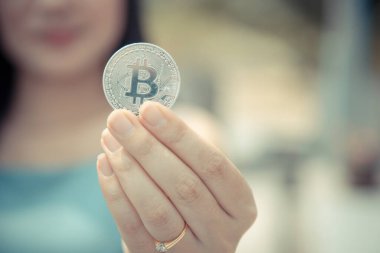 Elinde Bitcoin dijital para ve arka planı bulanık kripto para tutan güzel bir kadın. Kaşsız Toplum kavramı Web Sanal Para Madenciliği.