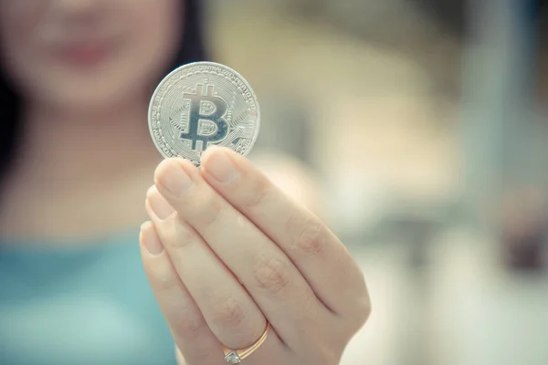 Elinde Bitcoin dijital para ve arka planı bulanık kripto para tutan güzel bir kadın. Kaşsız Toplum kavramı Web Sanal Para Madenciliği.