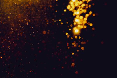 Siyah arkaplanla kutlama yapmak için kullanılan bulanık altın renkli parlak yıldızlar.