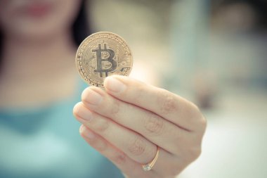 Elinde Bitcoin dijital para ve arka planı bulanık kripto para tutan güzel bir kadın. Kaşsız Toplum kavramı Web Sanal Para Madenciliği.