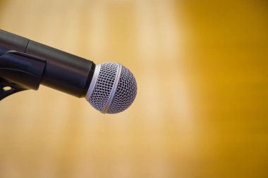 Oditoryumun altın arkaplanlı bir kürsüsündeki mikrofonu kapat.