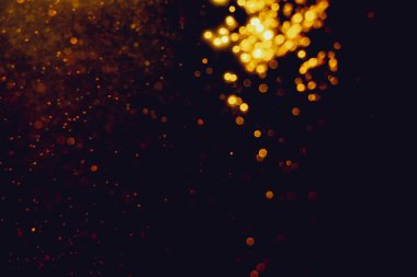 Siyah arkaplanla kutlama yapmak için kullanılan bulanık altın renkli parlak yıldızlar.