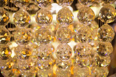 Güzel kristal avizeler fırçalanmış cam kristaller arasından yansıyan sıcak ışık Bokeh arka planlı klasik avizeye asılı.