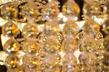 Güzel kristal avizeler fırçalanmış cam kristaller arasından yansıyan sıcak ışık Bokeh arka planlı klasik avizeye asılı.