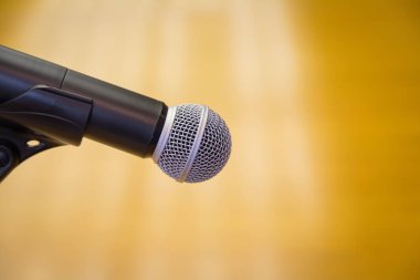 Oditoryumun altın arkaplanlı bir kürsüsündeki mikrofonu kapat.