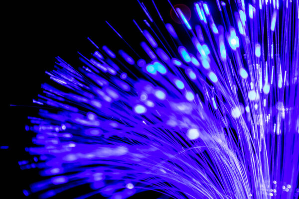 Close up of blurred light fiber optics for communication technology network on black background