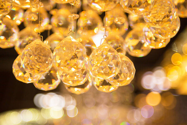 Beautiful crystal chandeliers warm light reflecting through brushed czech glass crystals hanging on vintage chandelier with bokeh background