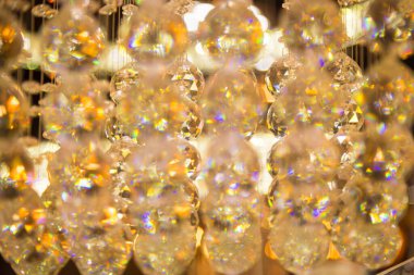 Güzel kristal avizeler fırçalanmış cam kristaller arasından yansıyan sıcak ışık Bokeh arka planlı klasik avizeye asılı.