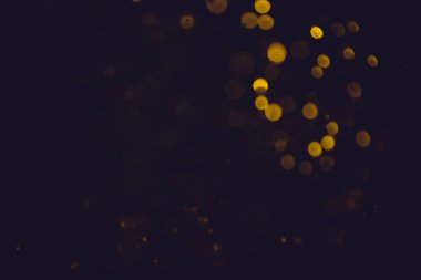 Siyah arkaplanı olan neon ışıkları tarafından soyut altın rengi bokeh bulanıklığı giderilir