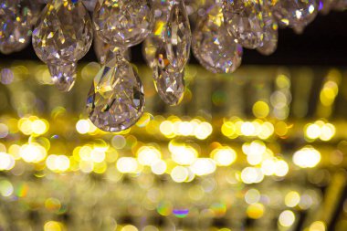 Güzel kristal avizeler fırçalanmış cam kristaller arasından yansıyan sıcak ışık Bokeh arka planlı klasik avizeye asılı.