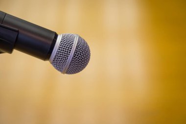 Oditoryumun altın arkaplanlı bir kürsüsündeki mikrofonu kapat.