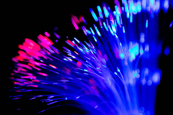 Close up of blurred light fiber optics for communication technology network on black background