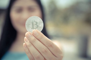Elinde Bitcoin dijital para ve arka planı bulanık kripto para tutan güzel bir kadın. Kaşsız Toplum kavramı Web Sanal Para Madenciliği.
