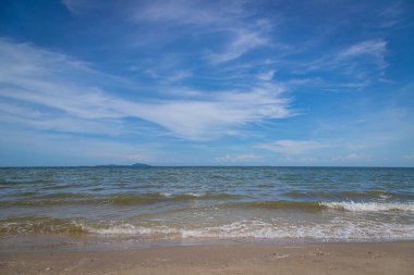 Kumsalda kumlar, deniz ve mavi gökyüzü arka planı.