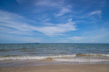 Kumsalda kumlar, deniz ve mavi gökyüzü arka planı.
