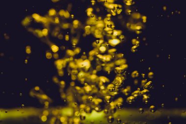 Noel Altını Parıltılı Işıklar Festivali 'nin soyutlaması. Sudan çıkarılmış parlak bokeh, siyah arka planla dağılmış.