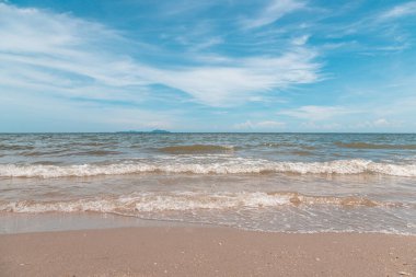 Kumsalda kumlar, deniz ve mavi gökyüzü arka planı.