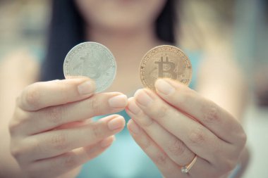 Elinde Bitcoin dijital para ve arka planı bulanık kripto para tutan güzel bir kadın. Kaşsız Toplum kavramı Web Sanal Para Madenciliği.