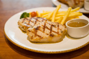 Kızarmış domuz bifteği, yanında patates kızartması ve sebze.