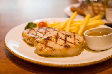 Kızarmış domuz bifteği, yanında patates kızartması ve sebze.