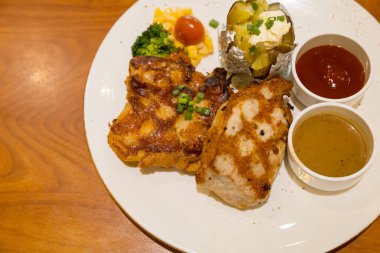 Izgara domuz bifteği, patates püresi ve sebzeyle servis edilir.