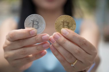 Elinde Bitcoin dijital para ve arka planı bulanık kripto para tutan güzel bir kadın. Kaşsız Toplum kavramı Web Sanal Para Madenciliği.