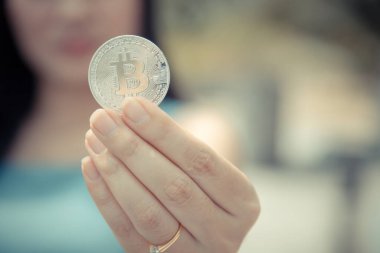 Elinde Bitcoin dijital para ve arka planı bulanık kripto para tutan güzel bir kadın. Kaşsız Toplum kavramı Web Sanal Para Madenciliği.