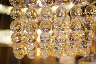 Güzel kristal avizeler fırçalanmış cam kristaller arasından yansıyan sıcak ışık Bokeh arka planlı klasik avizeye asılı.