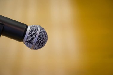 Oditoryumun altın arkaplanlı bir kürsüsündeki mikrofonu kapat.