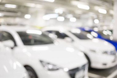 Binanın altındaki otoparkta park halindeki birçok arabanın görüntüsü bulanık. Alışveriş merkezine alışverişe gitmek için. Güvenli, parlak bir park yeri var..