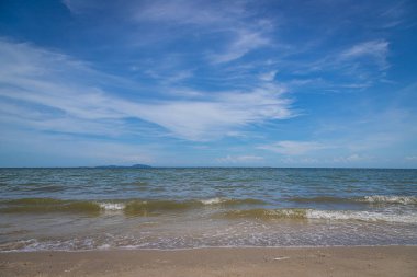 Kumsalda kumlar, deniz ve mavi gökyüzü arka planı.