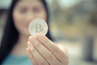 Elinde Bitcoin dijital para ve arka planı bulanık kripto para tutan güzel bir kadın. Kaşsız Toplum kavramı Web Sanal Para Madenciliği.