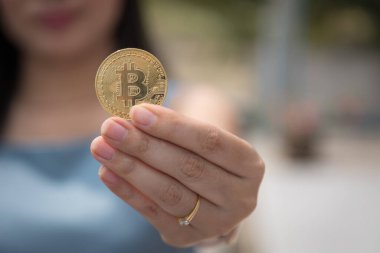Elinde Bitcoin dijital para ve arka planı bulanık kripto para tutan güzel bir kadın. Kaşsız Toplum kavramı Web Sanal Para Madenciliği.