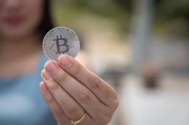 Elinde Bitcoin dijital para ve arka planı bulanık kripto para tutan güzel bir kadın. Kaşsız Toplum kavramı Web Sanal Para Madenciliği.
